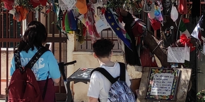 bambini di spalle davanti a fiori commemorativi